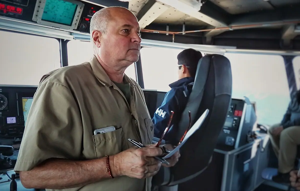 Officier de navigation sur la passerelle d'un navire, écrans de navigation en arrière-plan